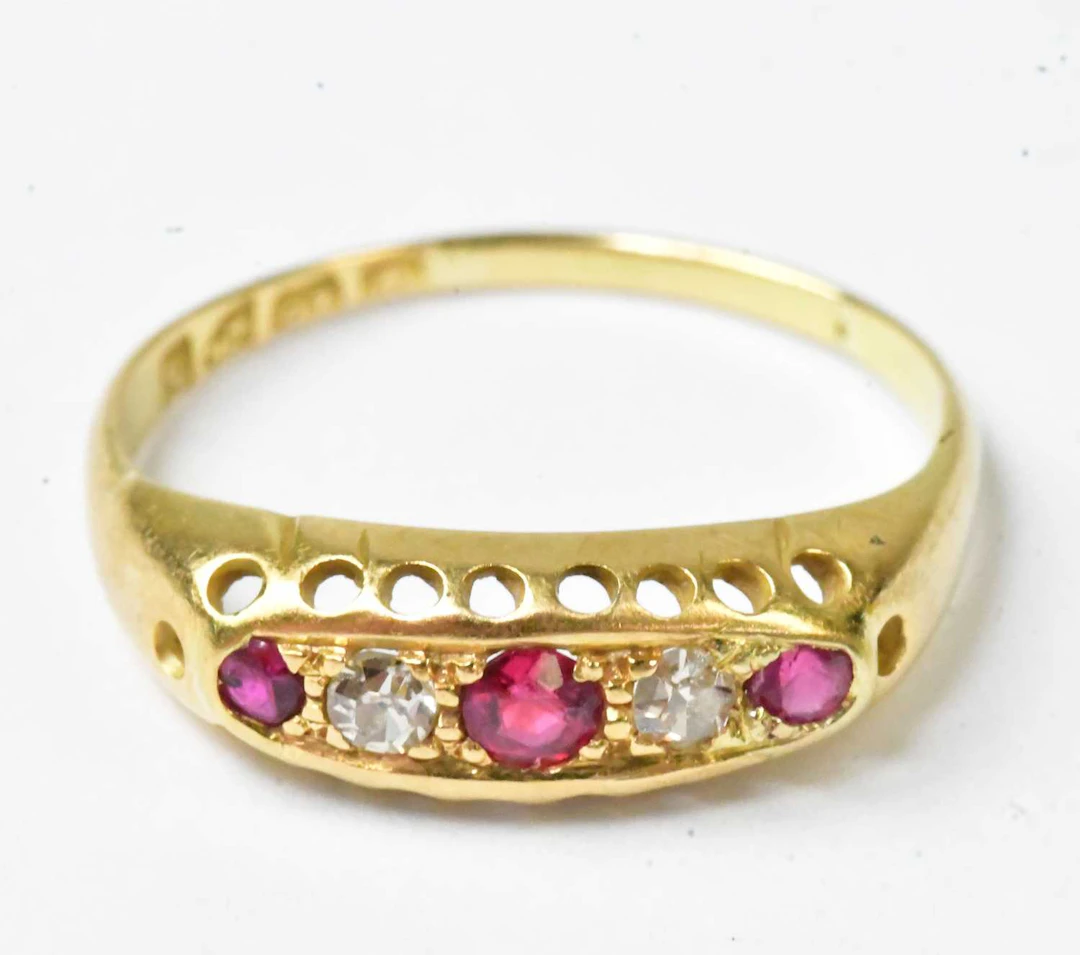 An 18ct yellow gold ring set with three red stones and two diamonds