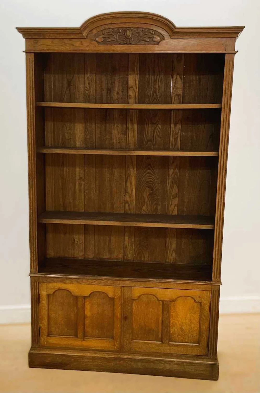 An oak open bookcase with a domed top having three adjustable shelves