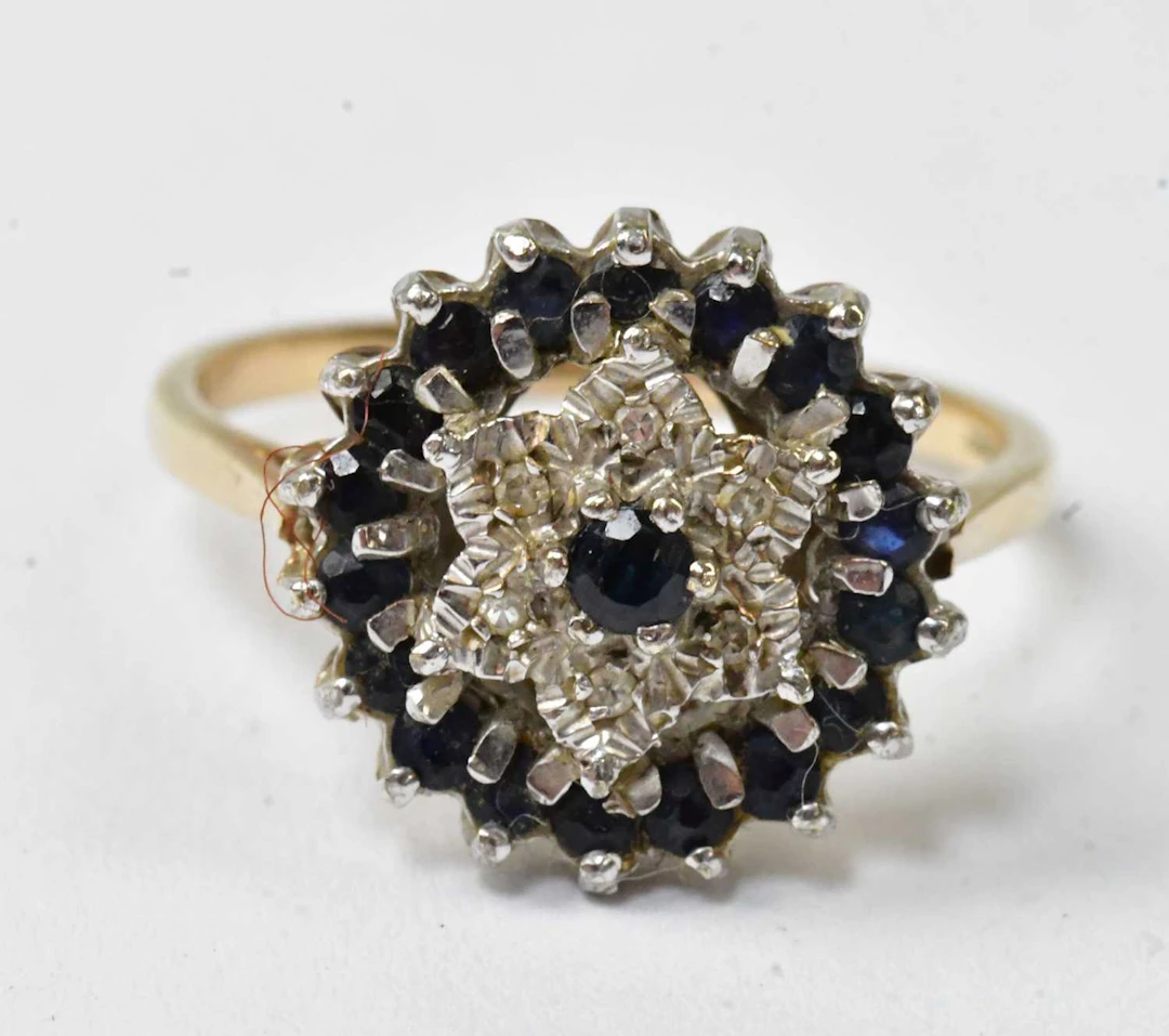 A 9ct yellow gold cluster ring set with a central blue...
