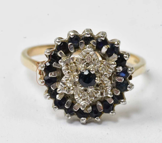 A 9ct yellow gold cluster ring set with a central blue...