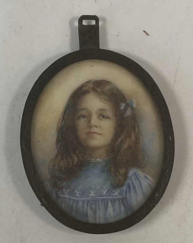 A 19th century oval portrait miniature of a young girl in a blue dress