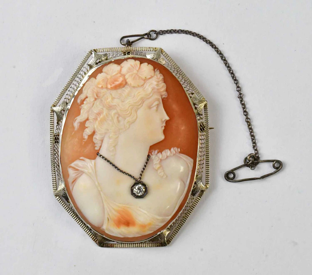 A large cameo brooch depicting a Classical maiden wearing...