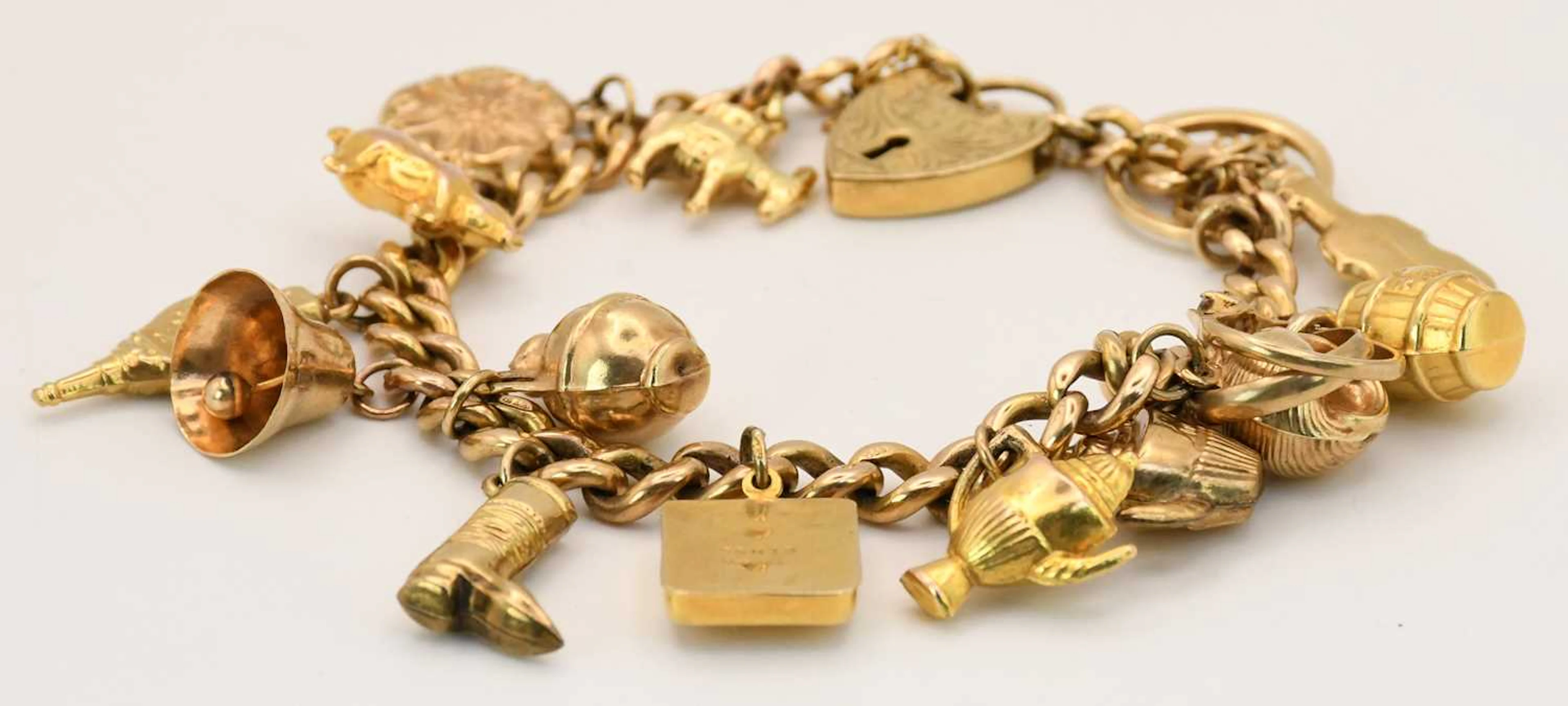 A 9ct yellow gold charm bracelet comprising fifteen...