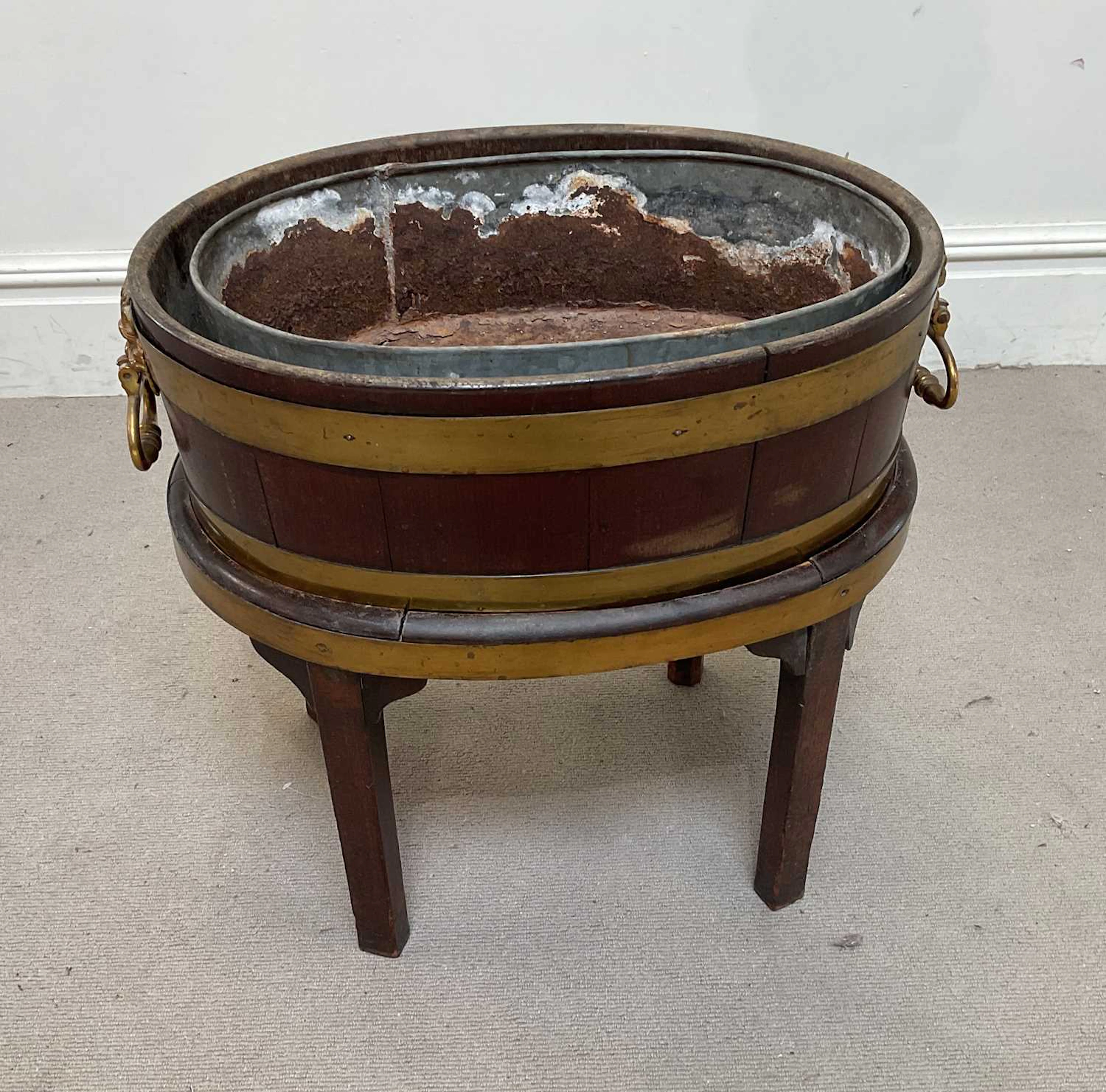 A Georgian mahogany and brass bound wine cooler of oval form