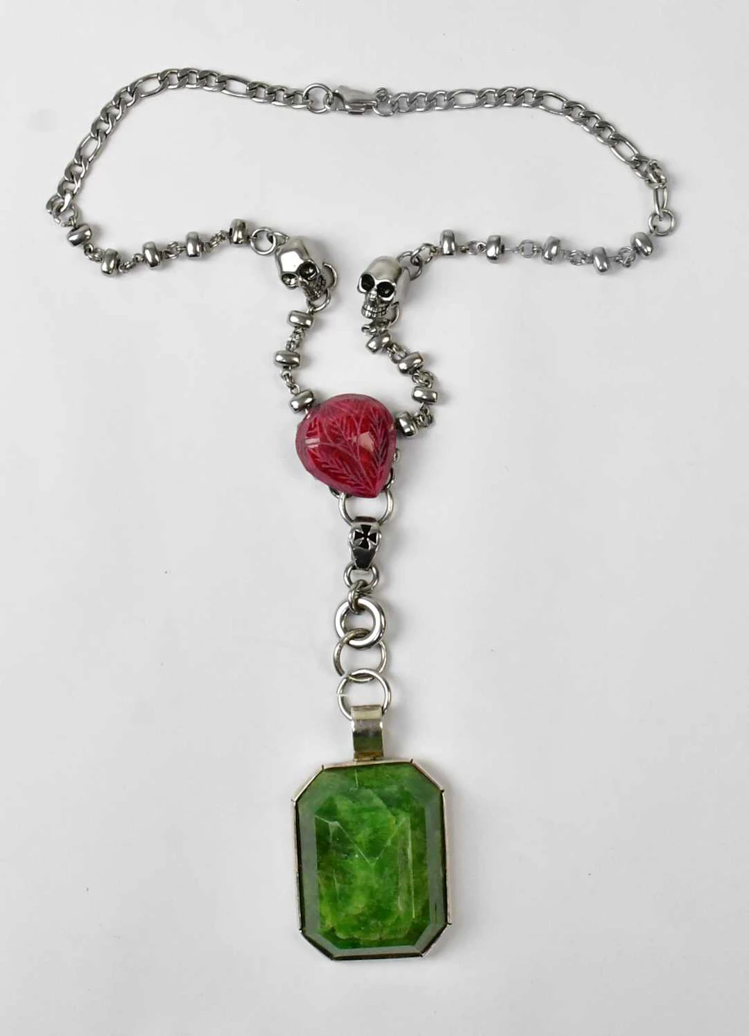 A silver-coloured chain necklace set with two skulls