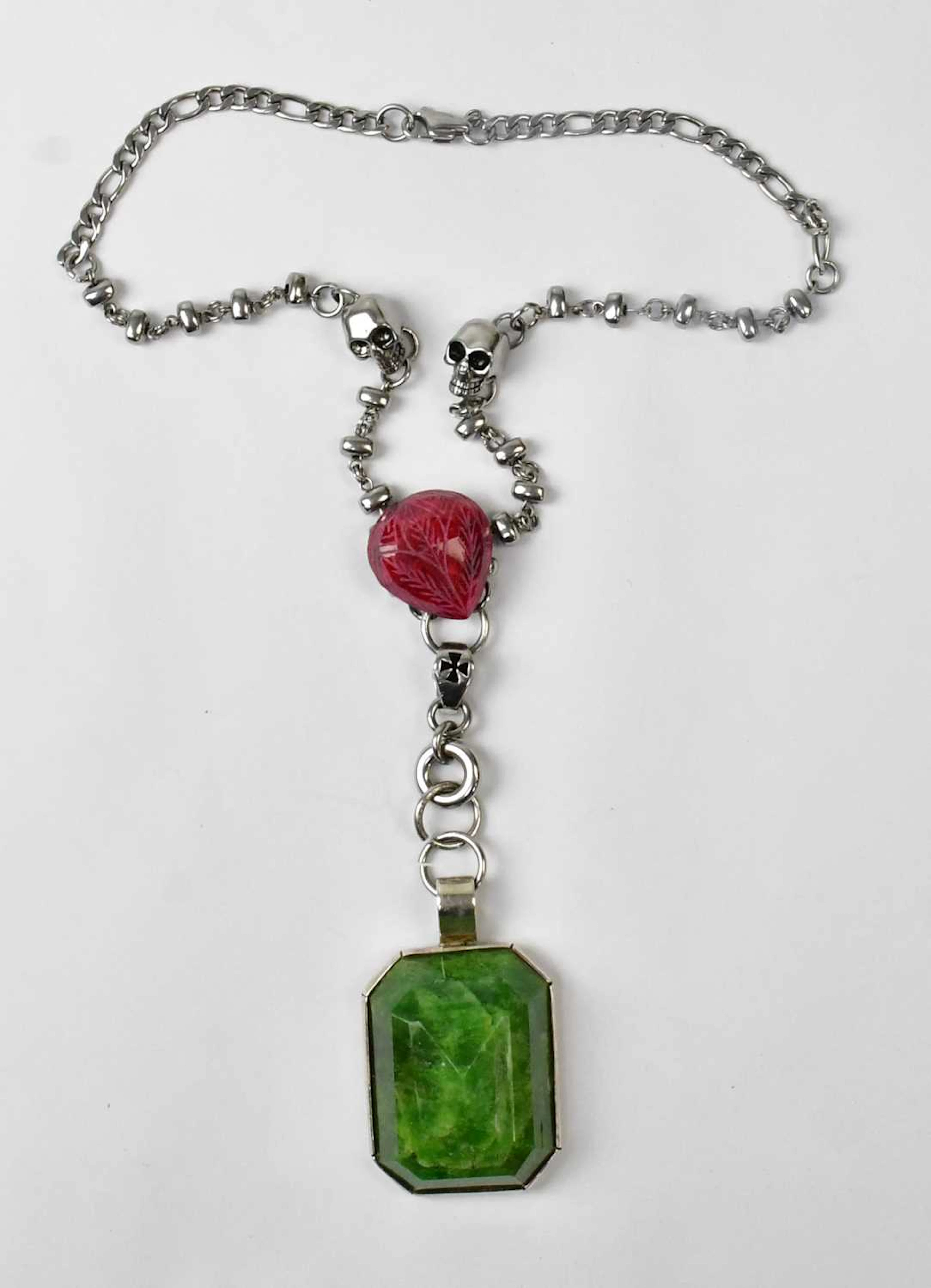 A silver-coloured chain necklace set with two skulls