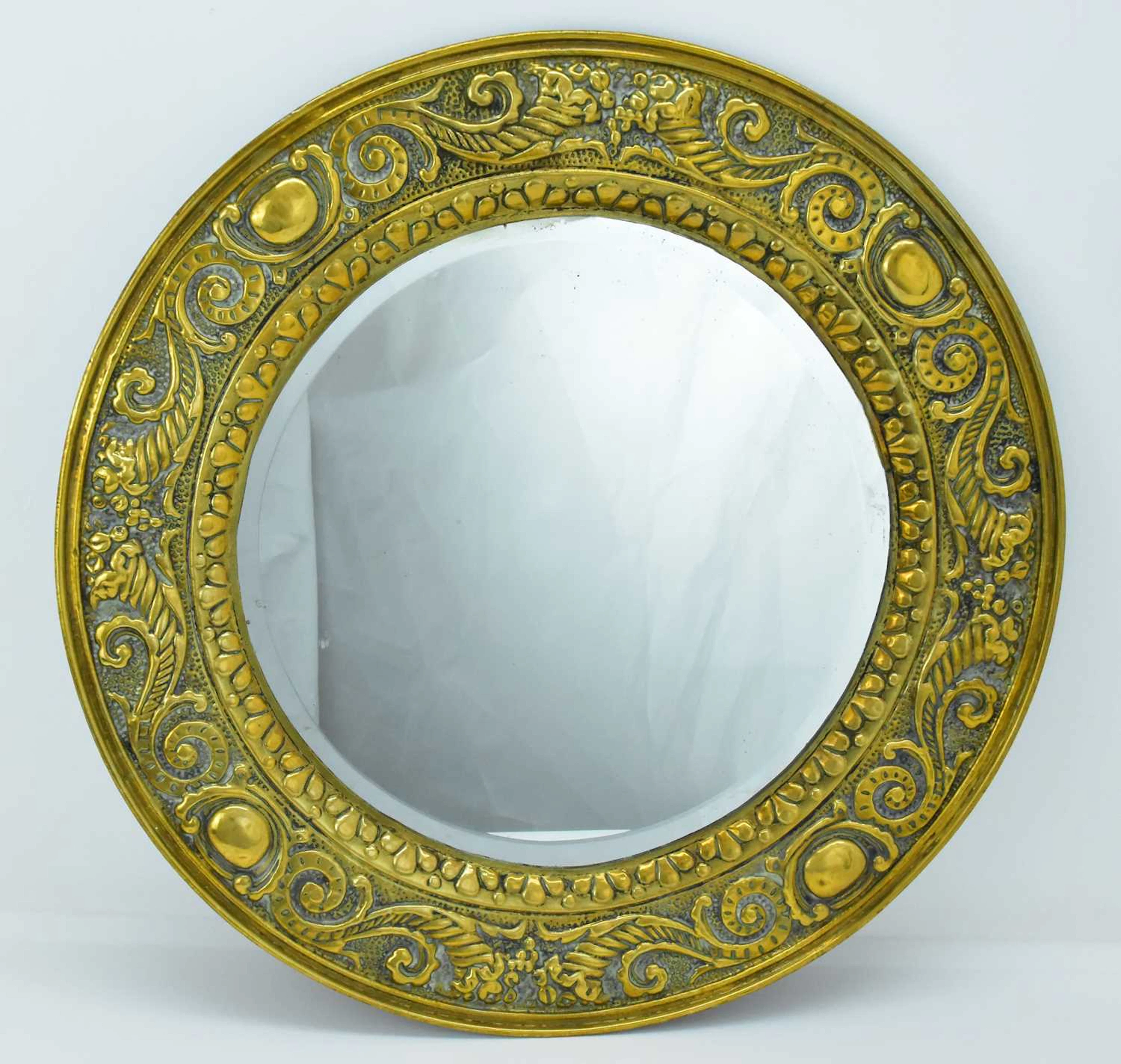 A large Arts and Crafts style press moulded brass circular mirror