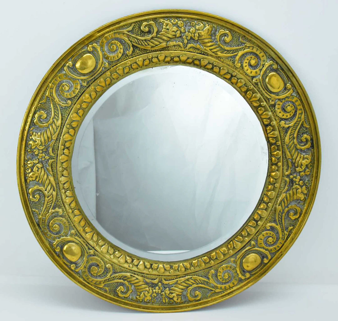 A large Arts and Crafts style press moulded brass circular mirror