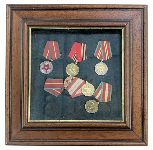 A framed montage of six Russian Soviet era military and commemorative medallions