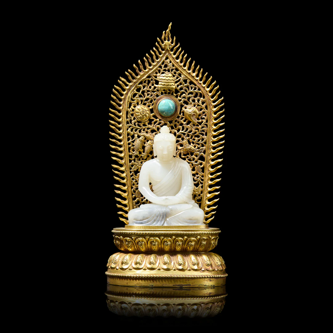 CHINESE WHITE JADE CARVING OF SHAKYAMUNI WITH GILT BRONZE STAND