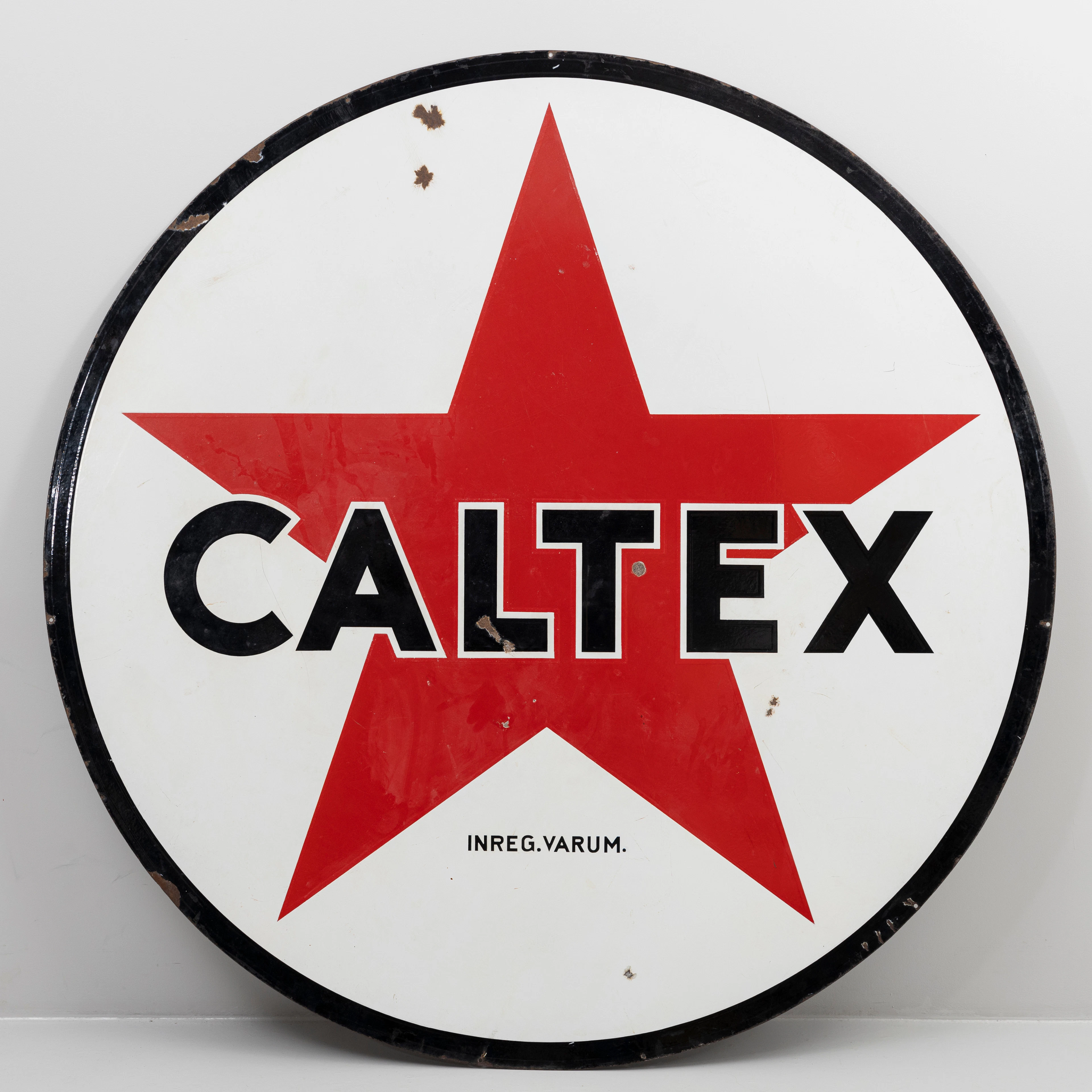 EMALJSKYLT CALTEX , dubbelsidig, svart röd text på vit botten, rund.