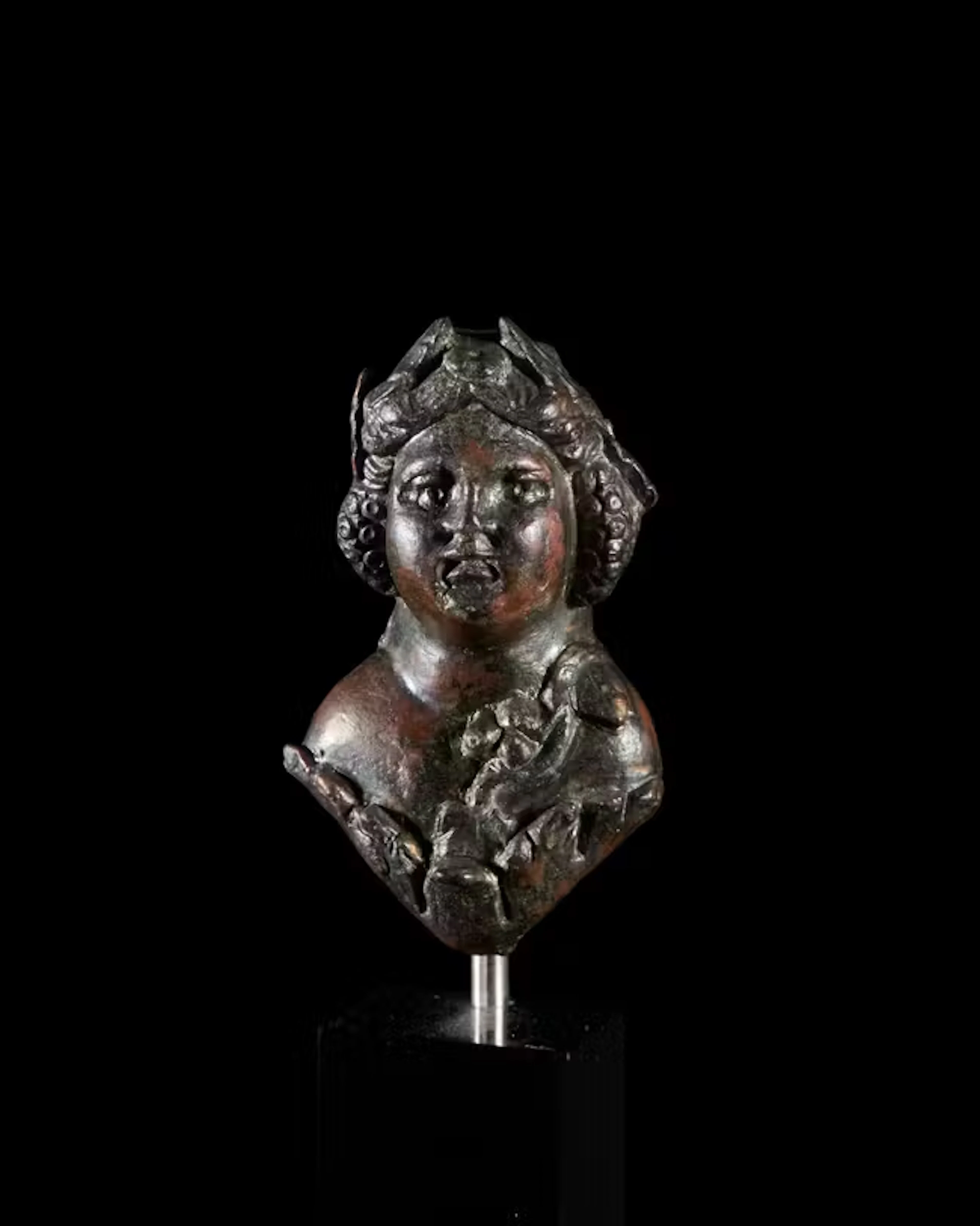 A Roman bronze bust of a childlike Bacchus wearing a...