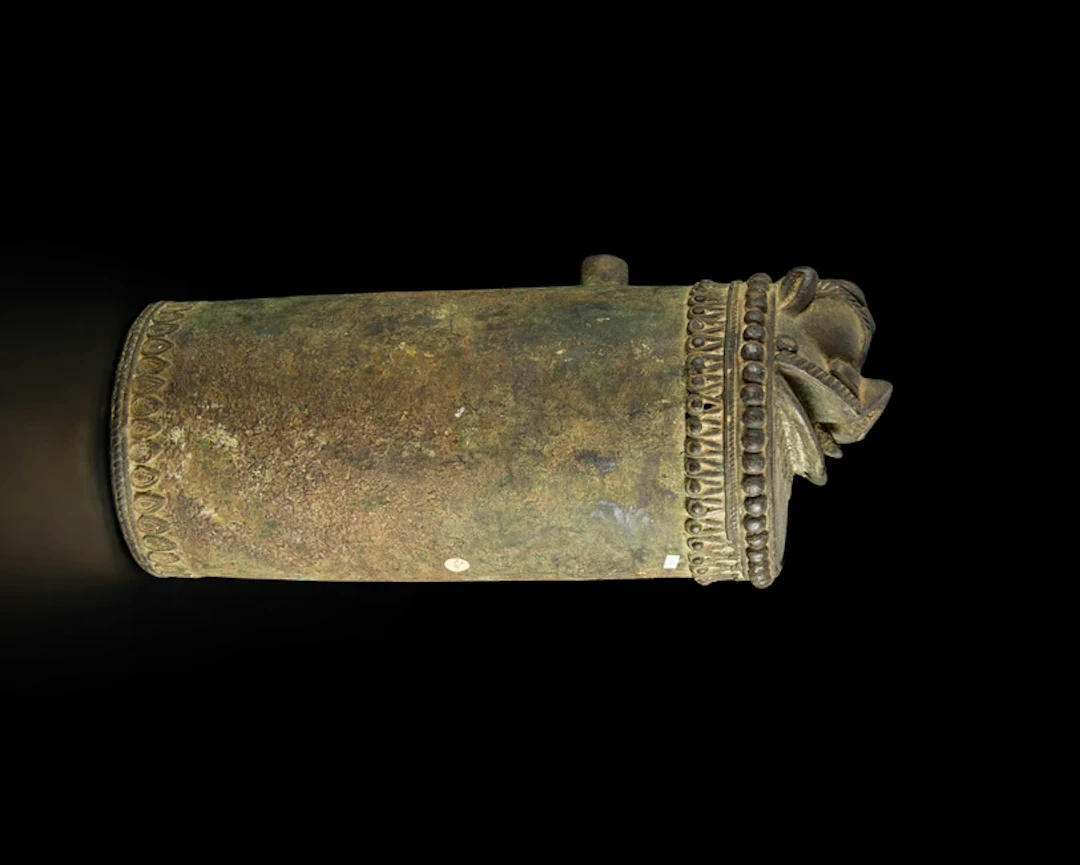A cylindrical bronze fountain spout or pole finial with a simplified makara head