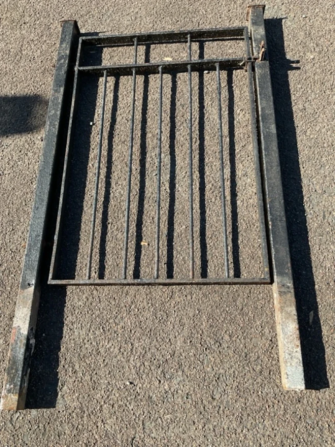 A wrought iron garden gate complete with two square capped gateposts