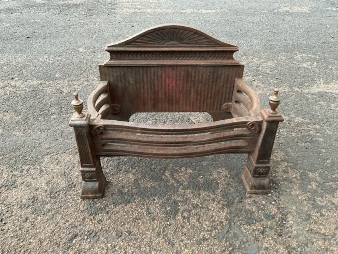 An Edwardian cast iron fire grate with arched fan cast backplate curved