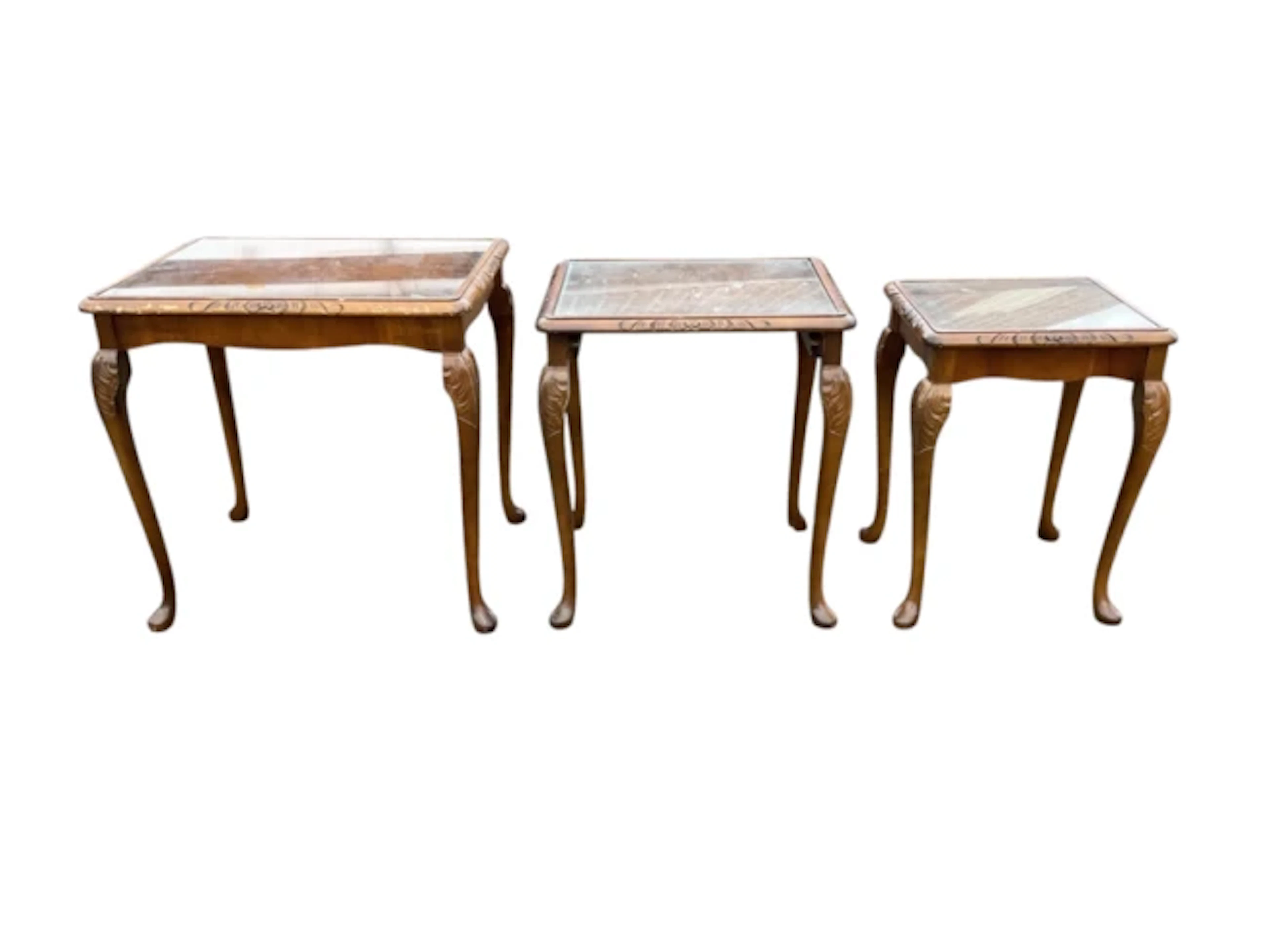 A nest of carved walnut tables with plate glass tops, raised on slender