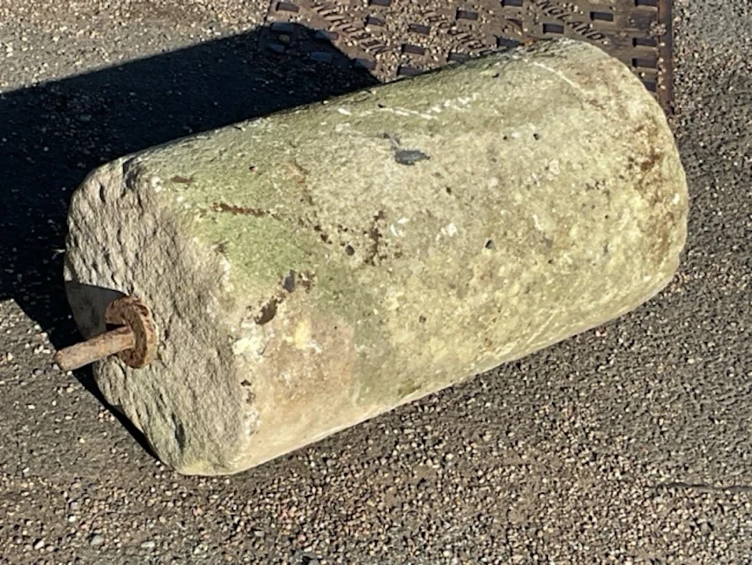 An ancient stone cylinder roller, the ends with iron axel type rods. (23in)