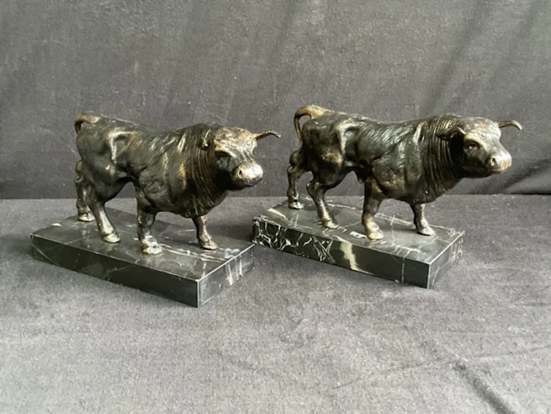A pair of cast bronze-patinated iron figures of bulls on rectangular