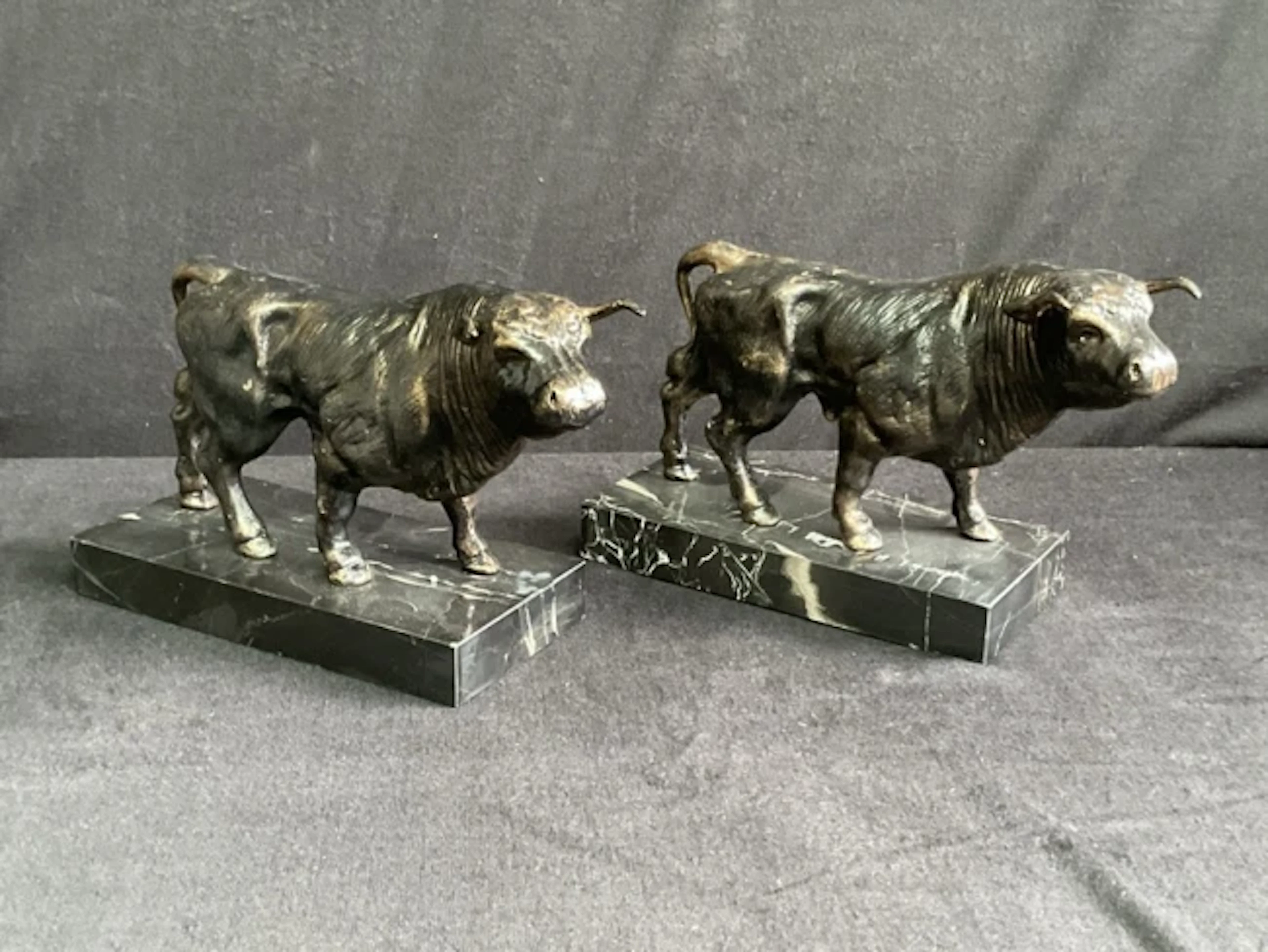 A pair of cast bronze-patinated iron figures of bulls on rectangular