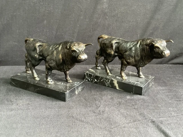 A pair of cast bronze-patinated iron bulls mounted on rectangular