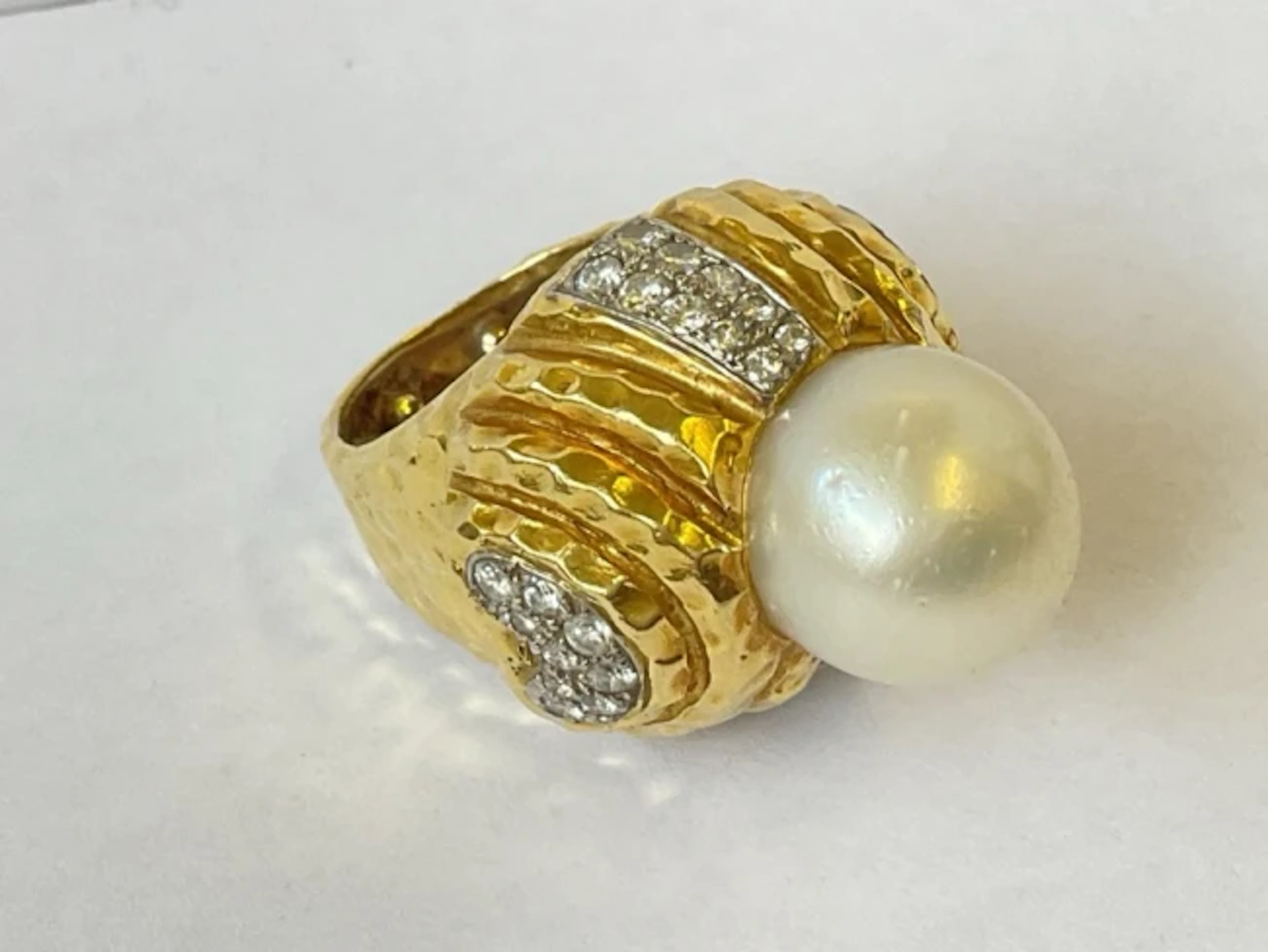 An 18ct gold ring, the beaten metal piece set with 1.5cm pearl & diamonds