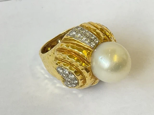 An 18ct gold ring, the hammered piece set with 1.5cm pearl and panels