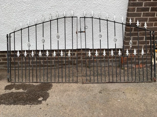 A pair of painted arched wrought iron driveway gates with spear finials