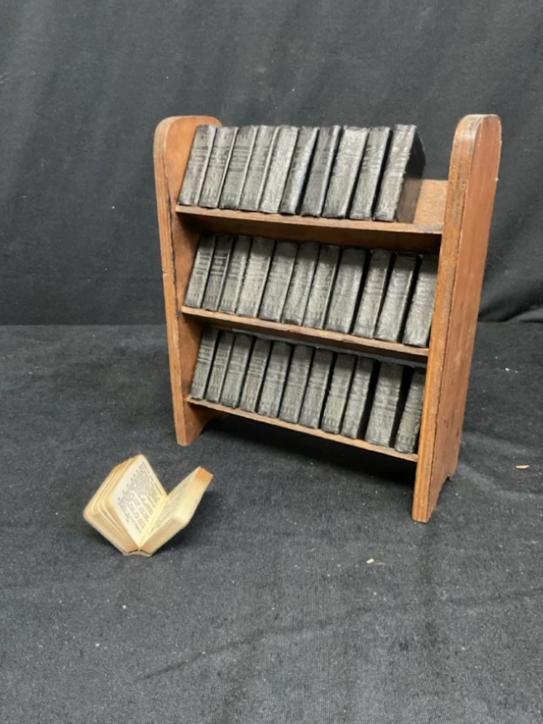 A 30s miniature bookcase containing 33 miniature leatherette bound