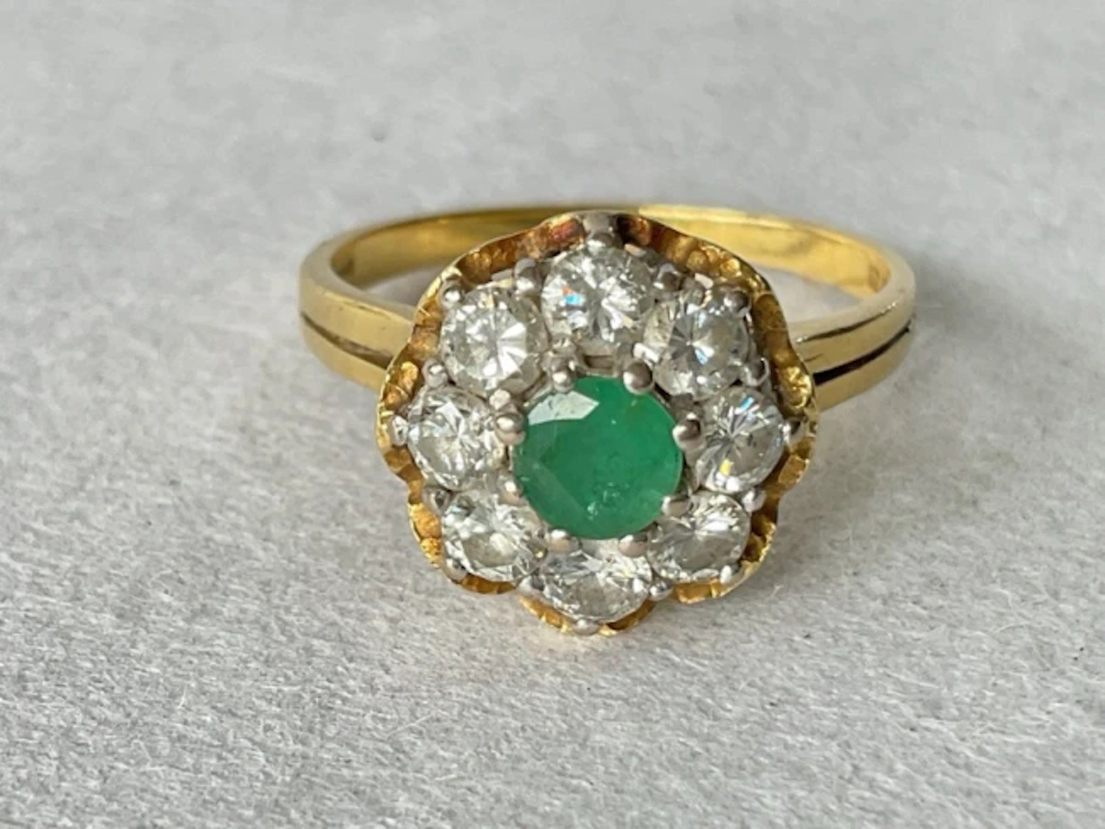 An 18ct gold cluster ring with central claw set emerald framed by