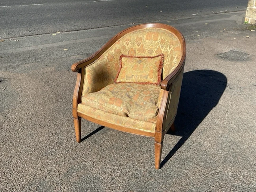 A mahogany armchair with rounded tub back and scrolled arms framing