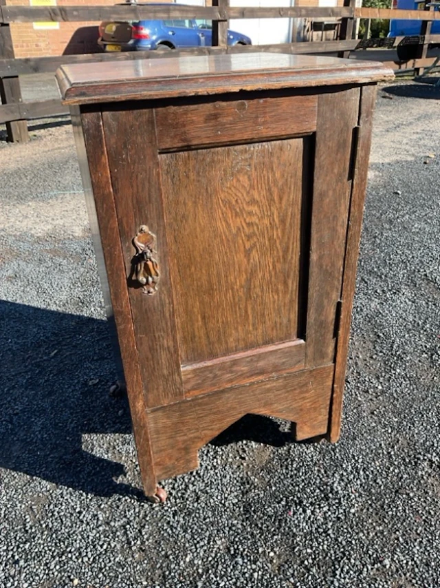 An Edwardian oak cupboard with moulded top above a panelled door and