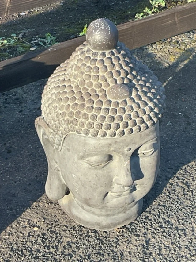 A composition buddha head with noduled hairpiece beneath ball finial