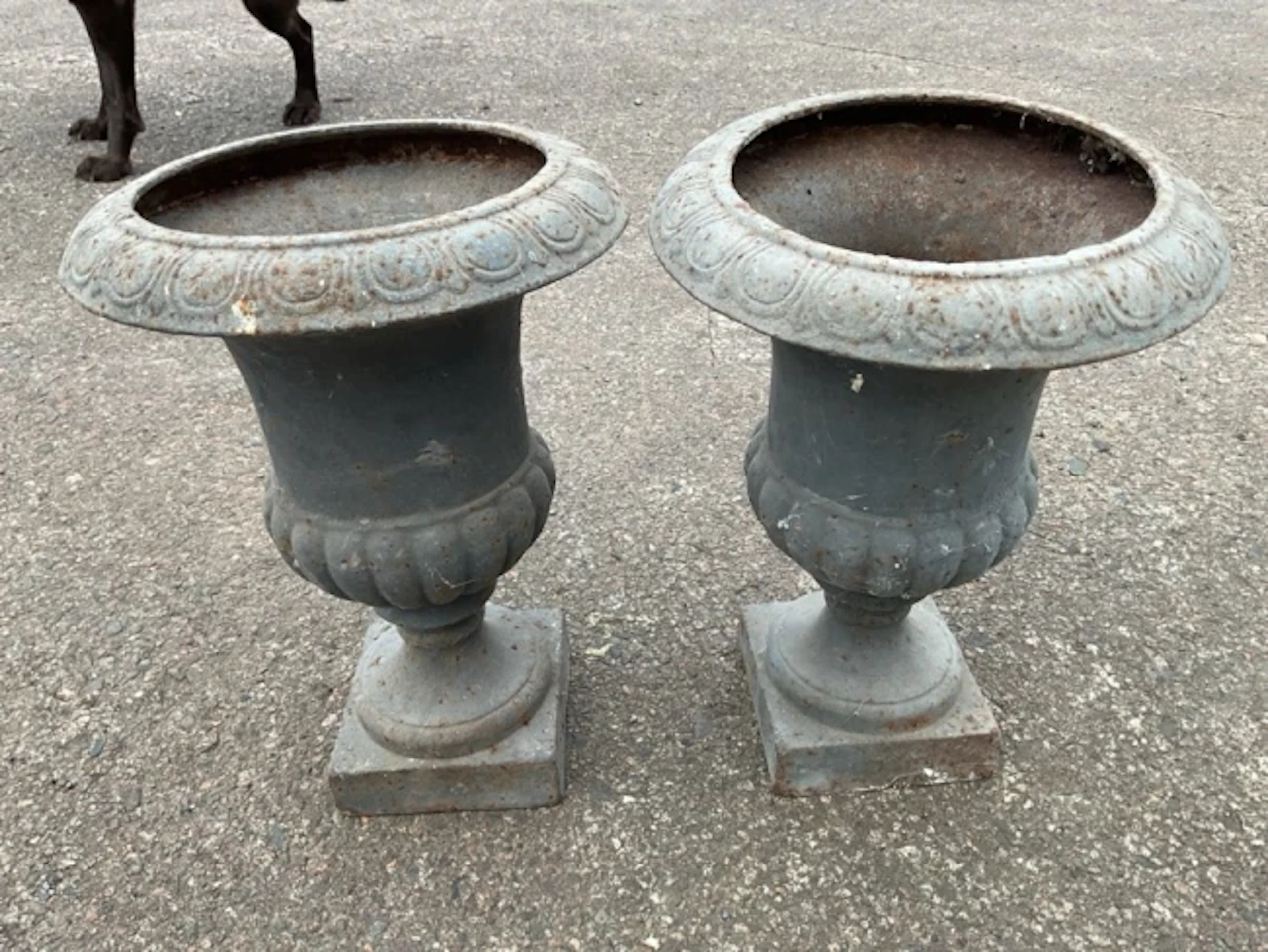 A pair of cast iron garden urns with lozenge moulded rims and fluted