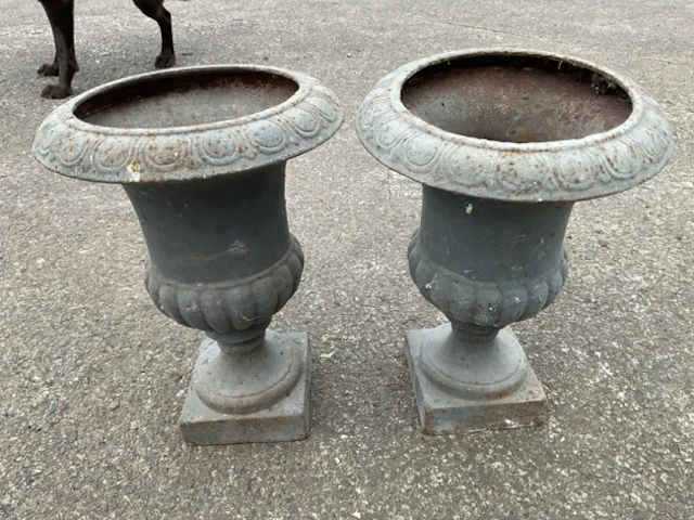 A pair of cast iron garden urns with lozenge moulded rims and fluted