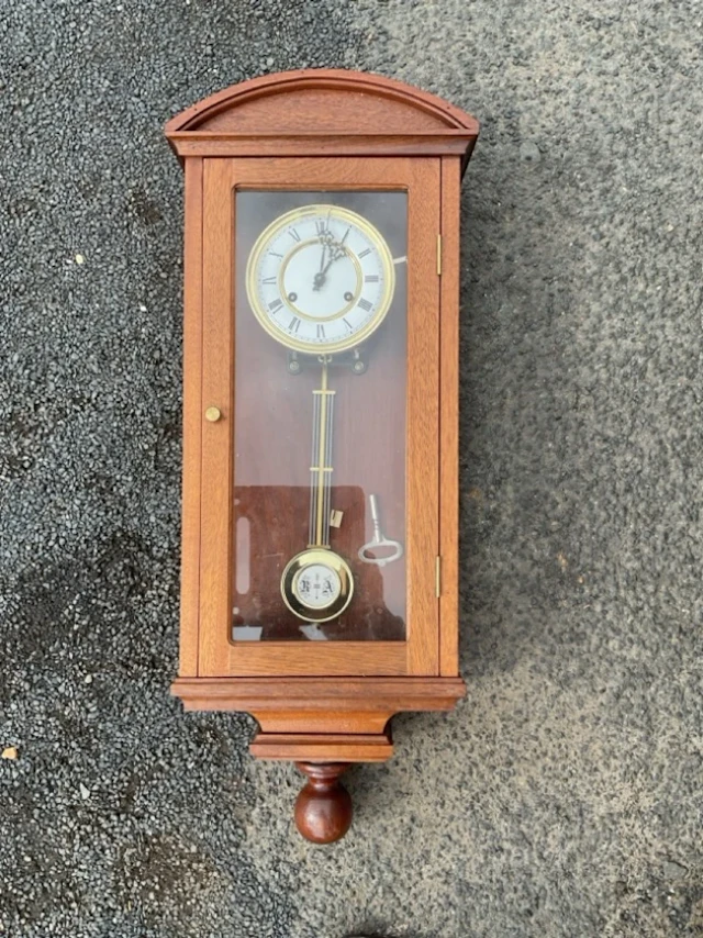 A Victorian style mahogany cased clock with arched cornice above glazed