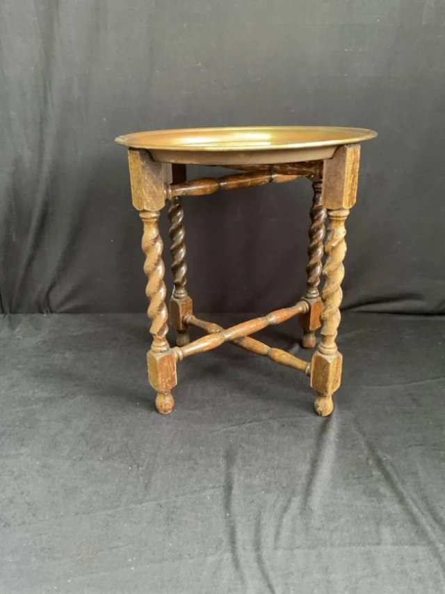 A circular brass tray-top table engraved with flowerheads on a folding