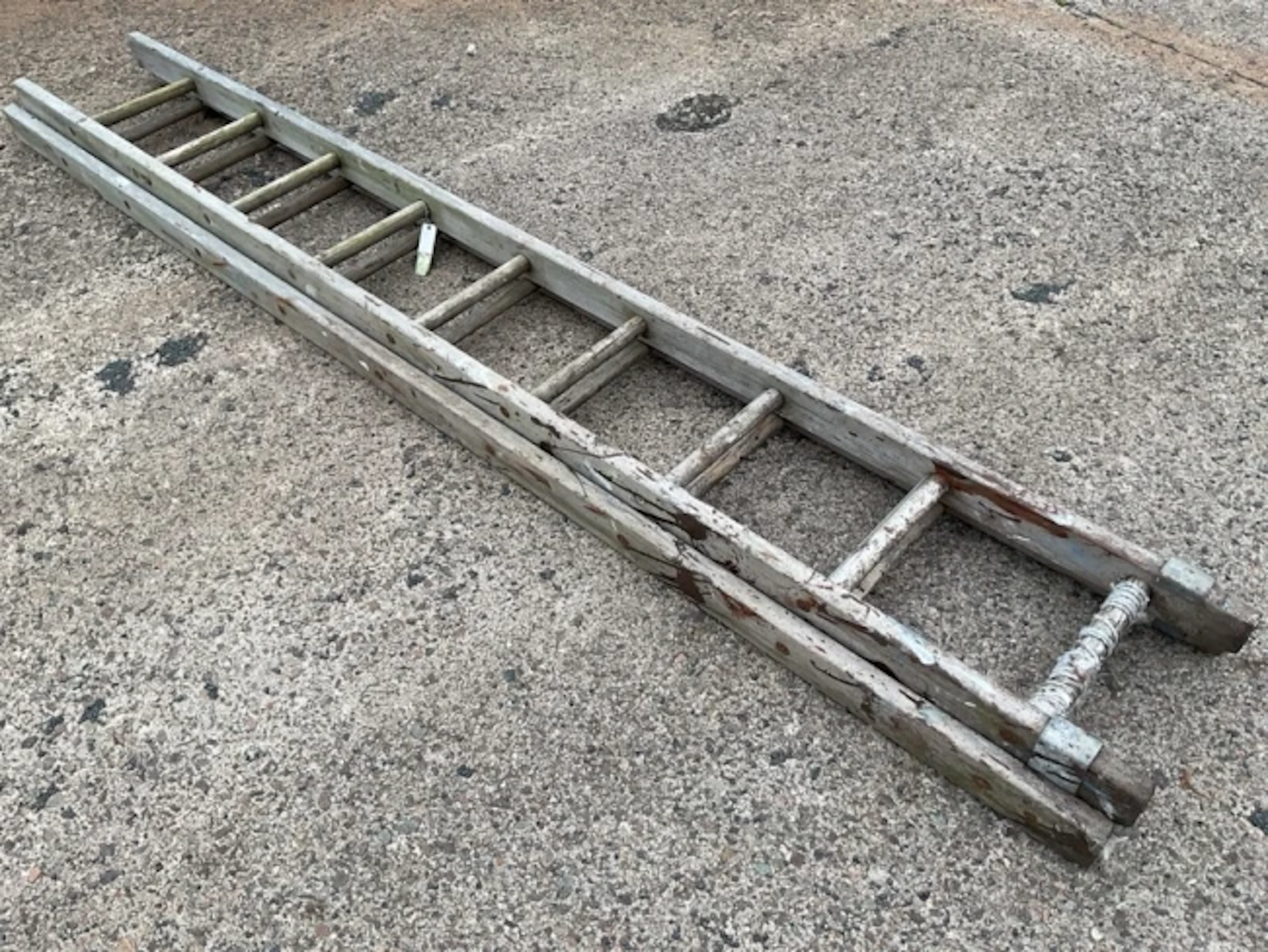A two-piece old wood extension ladder, each section with nine reinforced