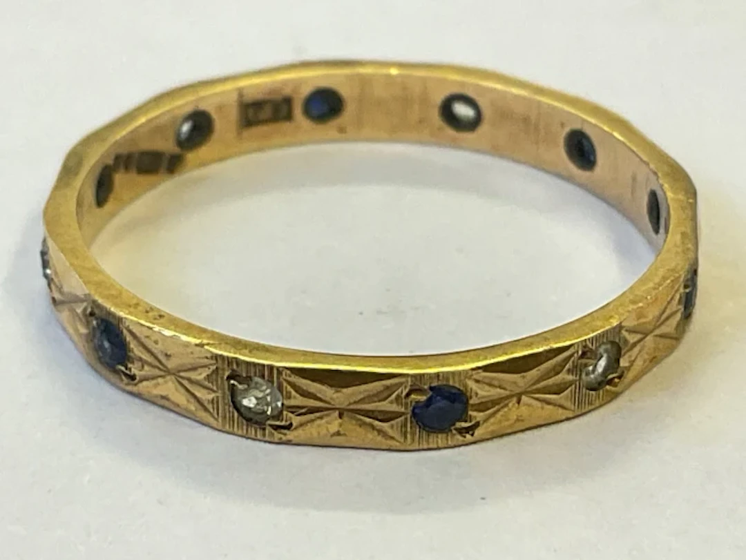 A hallmarked 9ct gold sapphire and zircon eternity ring with etched