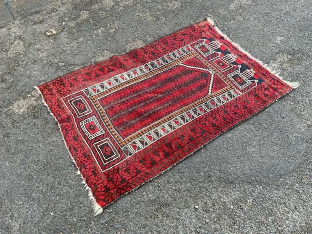 An Afghan Beluchi wool prayer rug with triple domed mihrab with red