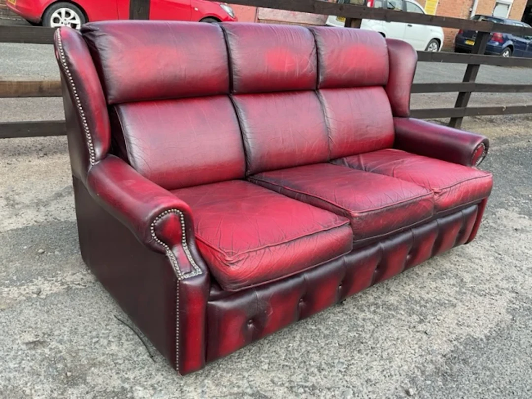A leather upholstered three-seater sofa with brass studding and loose