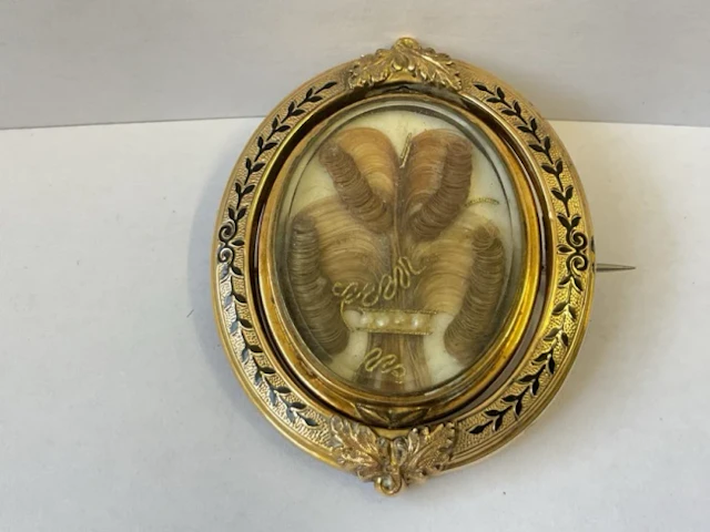 A Victorian memorial brooch with central oval lockets having plaited
