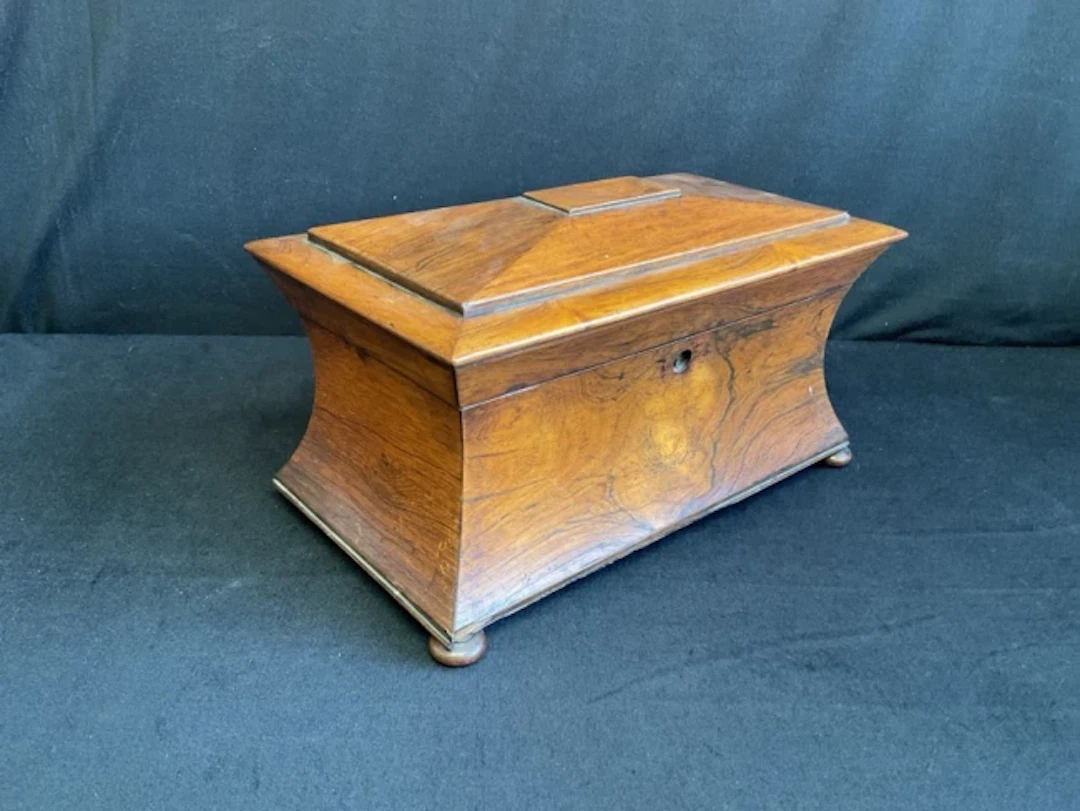 A Victorian rosewood tea caddy of waisted shape on bun feet, having