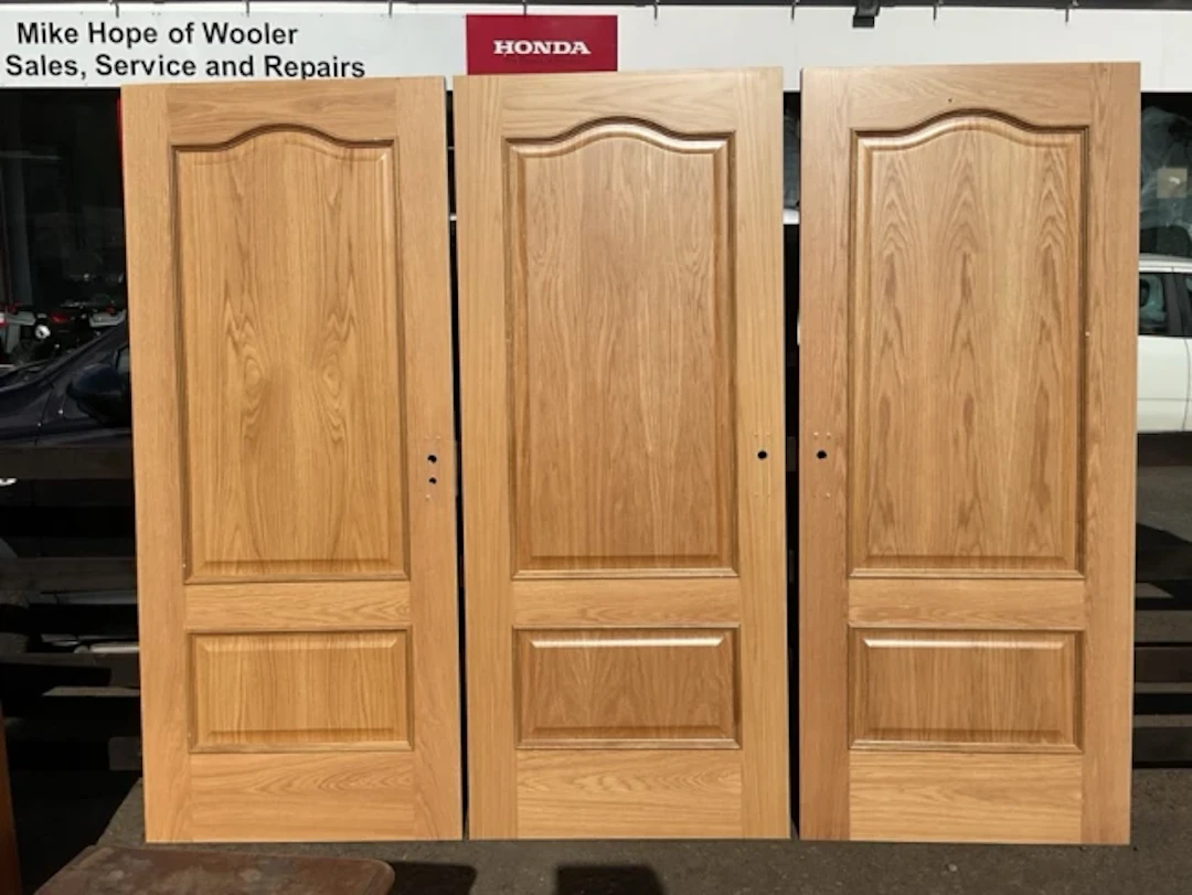 A set of three oak faced doors with arched moulded raised panels.