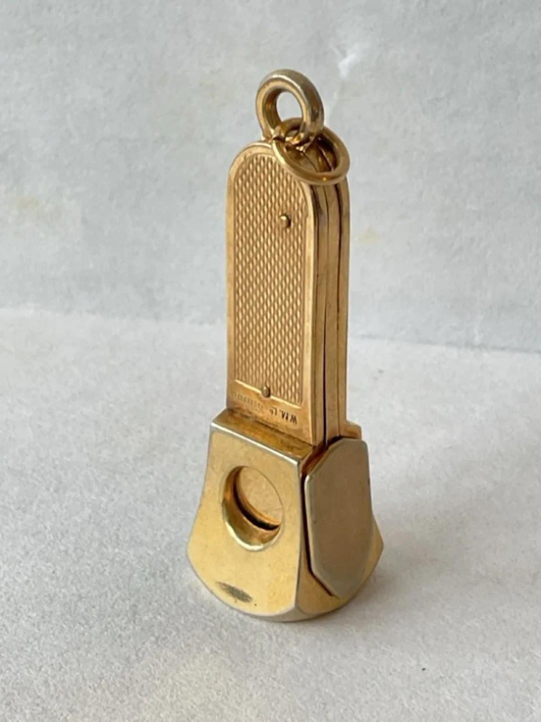 A gold plated fob cigar cutter with hinged action, having engine turned