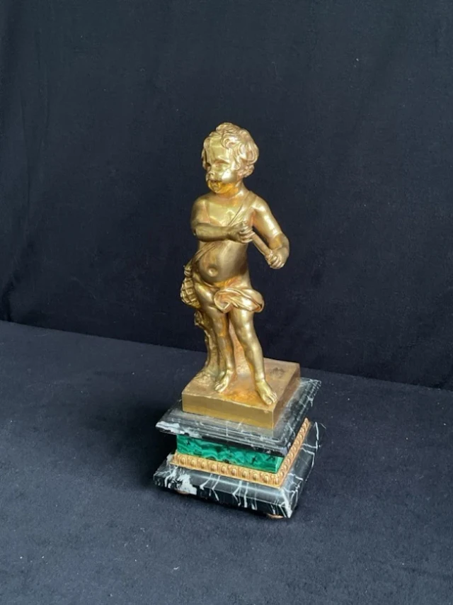 An C18th style gilt bronze putto fisherboy standing by a stump on