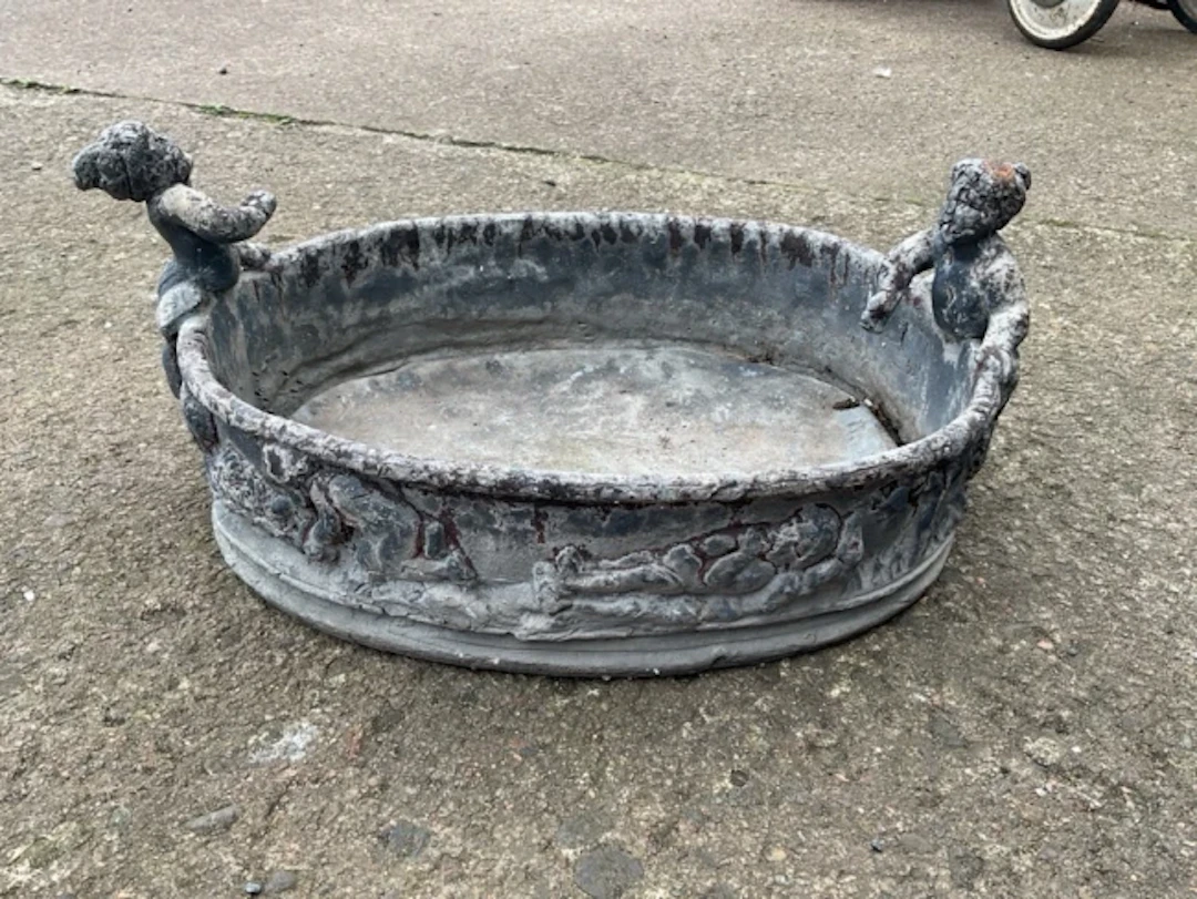 An oval nineteenth century lead garden tub cast with frieze of putti