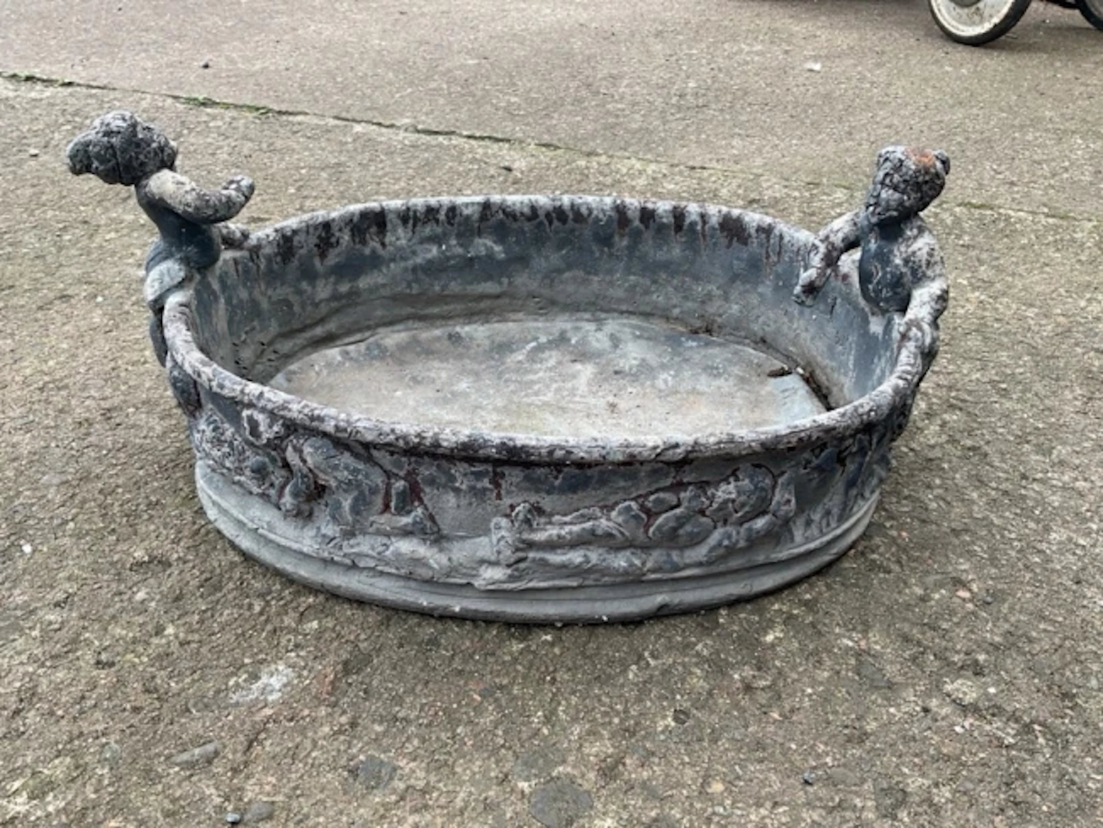 An oval nineteenth century lead garden tub cast with frieze of putti