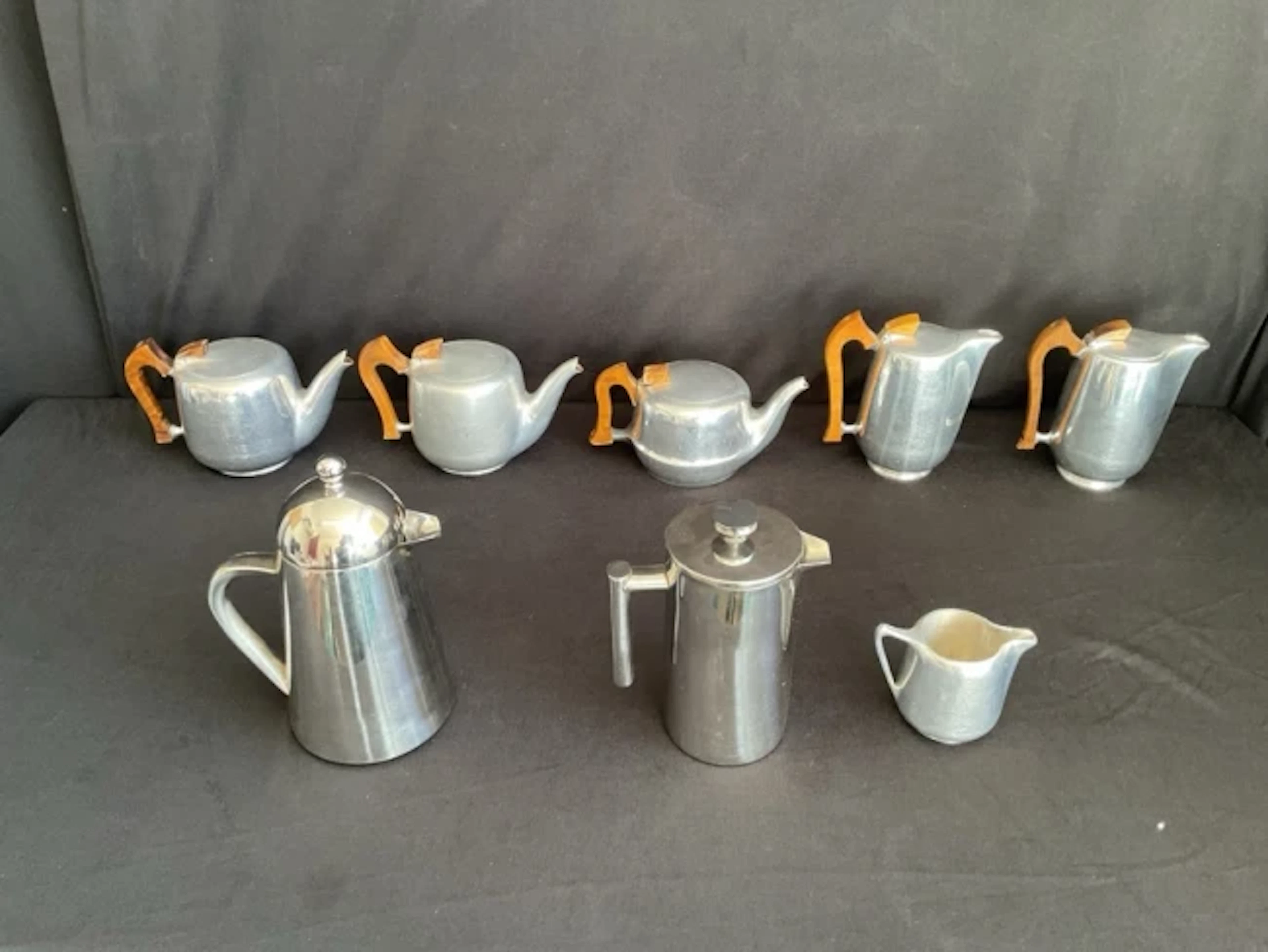 Three Piquot Ware cast aluminium teapots, two coffee pots and a cream