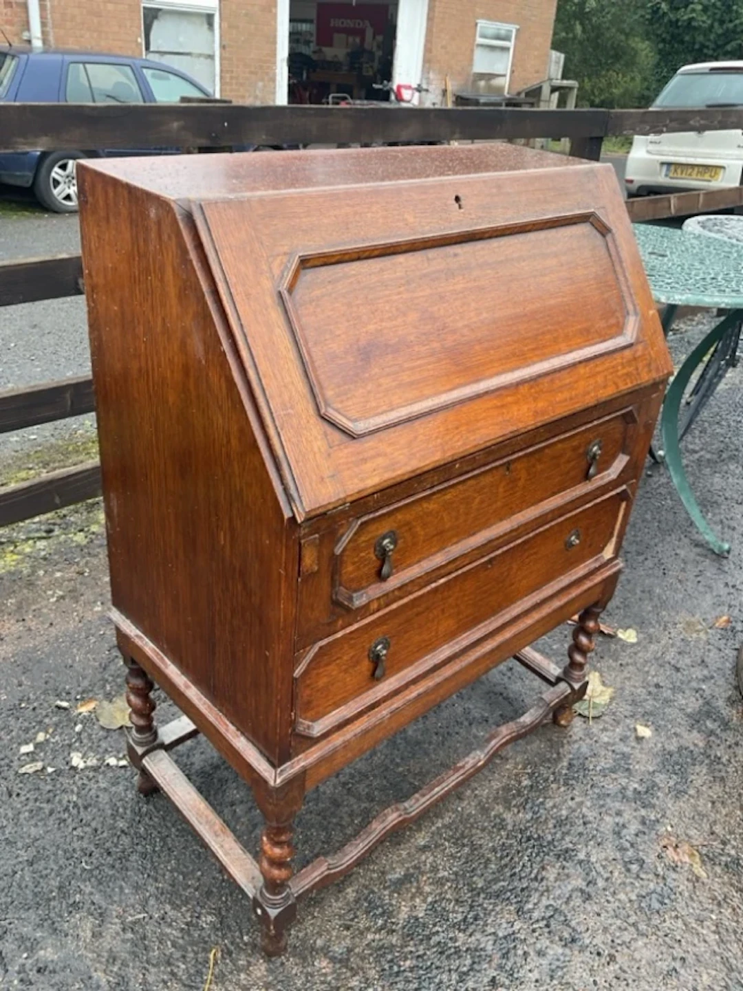 An oak bureau with panelled fall-front enclosing a fitted interior
