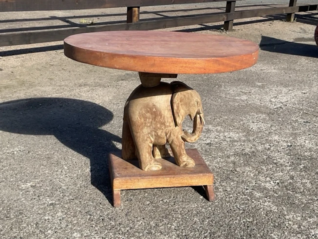 A mahogany coffee table, the thick circular top supported by a carved